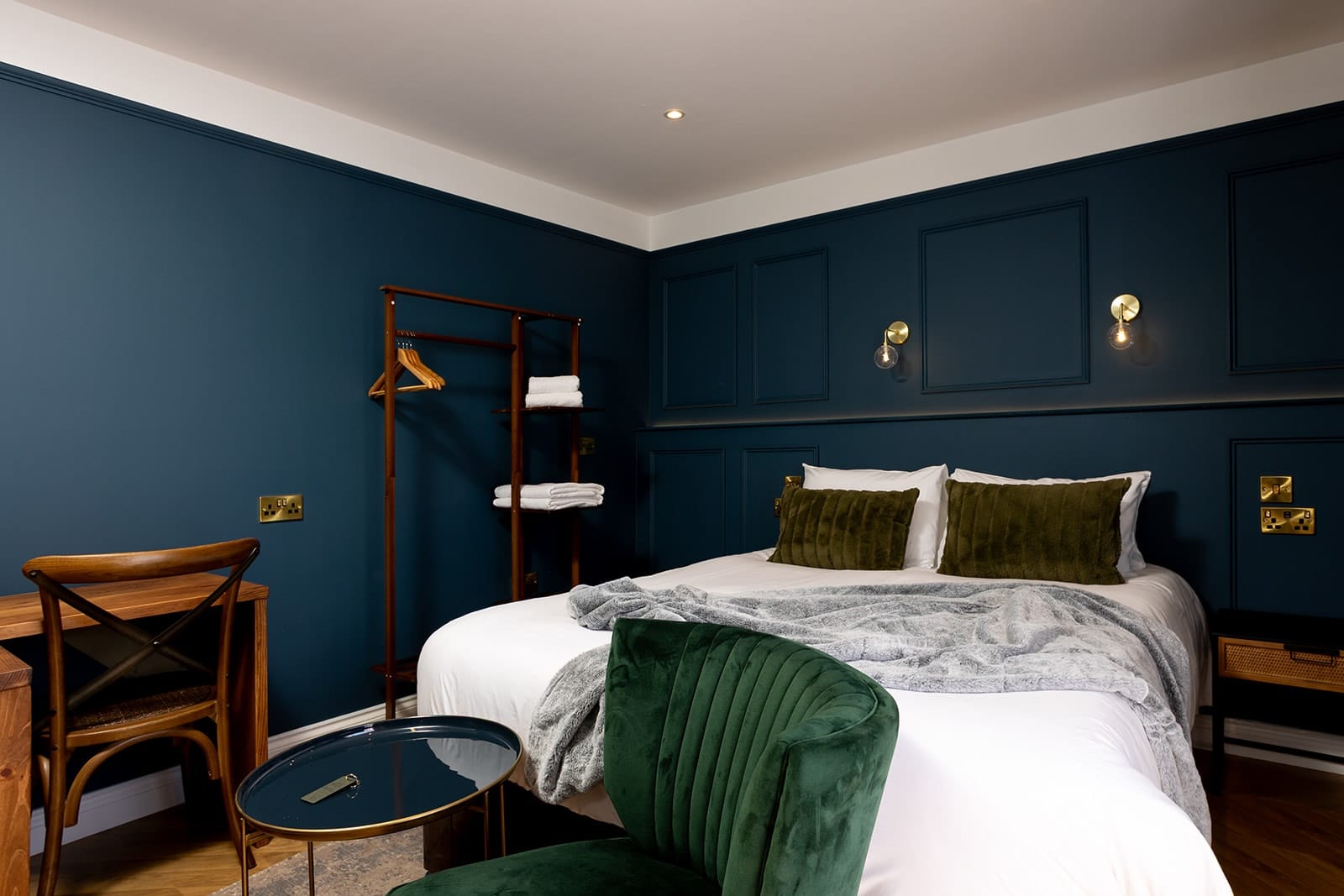 A cozy bedroom featuring blue walls and a neatly made bed