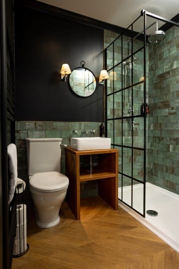 A modern bathroom featuring black walls and vibrant green tiles