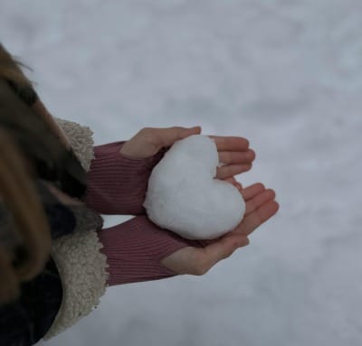 A person holds a heart-shaped snowball